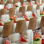 long tables with white cloths and brown chairs formal setting